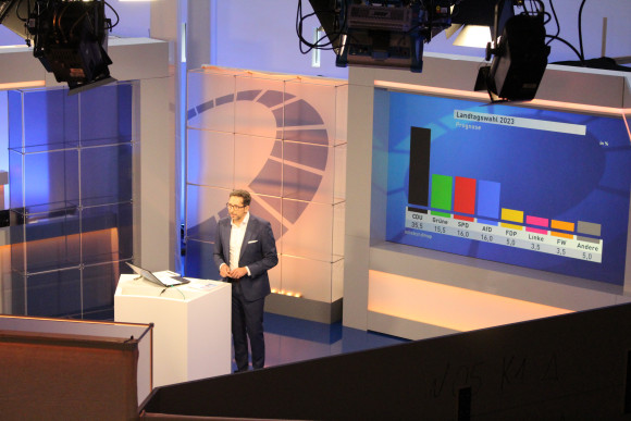 Ein Moderator stellt die erste Prognose der Landtagswahl vor
