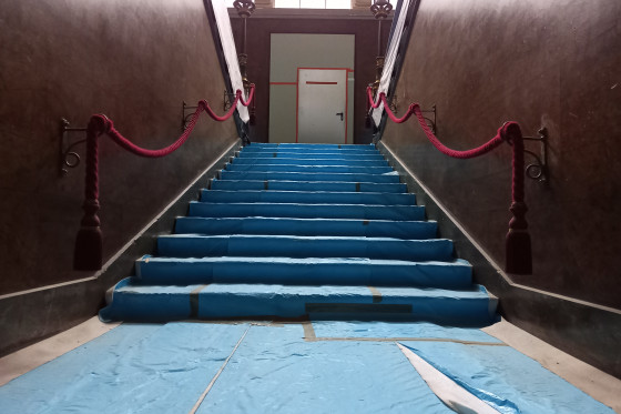Eine Treppe im Stadtschloss. Auf den Stufen sind blaue Plastikfolien ausgelegt.
