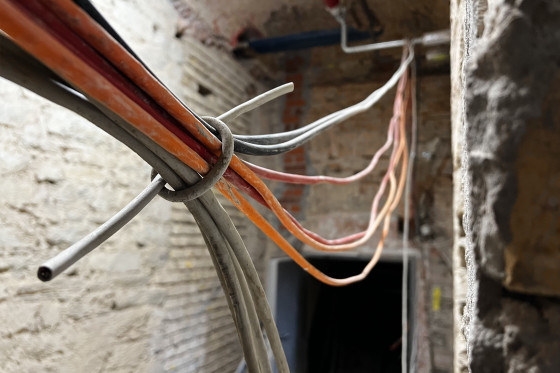 Verschiedene zusammengebundene Kabel hängen von der Decke in einem Raum der Baustelle Stadtschloss. 