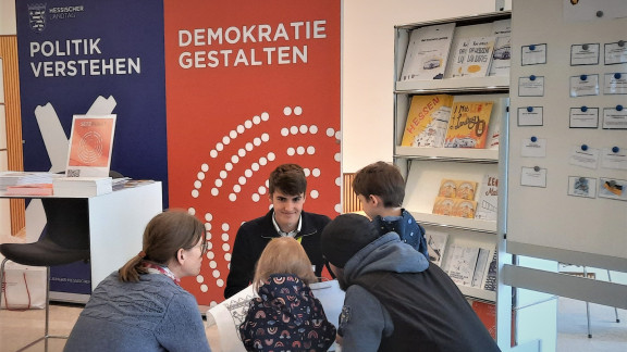 FSJ-ler Jakob spricht am Tag der offenen Tür mit einer Familie, die den Landtag besucht.