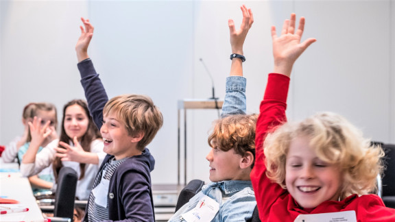 Lachende Kinder stimmen beim Planspiel "Der Kinder-Landtag" über einen Gesetzentwurf ab. 