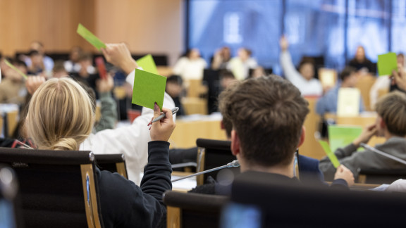 Jugendliche halten im Plenarsaal für eine Abstimmung grüne Kärtchen in die Luft.