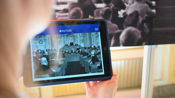 Die Illustration auf einem Tablet zeigt eine Plenarsitzung in den 1950er-Jahren. Damals wurde der Musiksaal des Stadtschlosses als Plenarsaal benutzt.