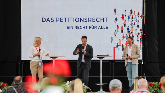Drei Personen auf Bühne diskutieren