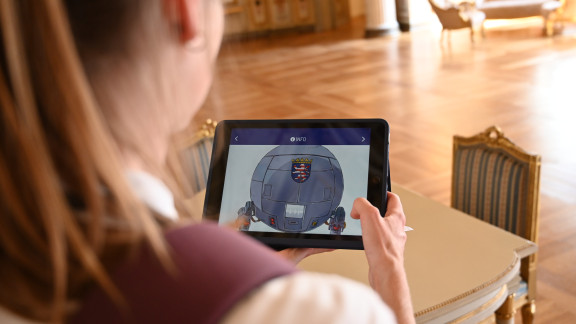 Die Illustration auf einem Tablet zeigt eine Plenarsitzung in den 1950er-Jahren. Damals wurde der Musiksaal des Stadtschlosses als Plenarsaal benutzt.