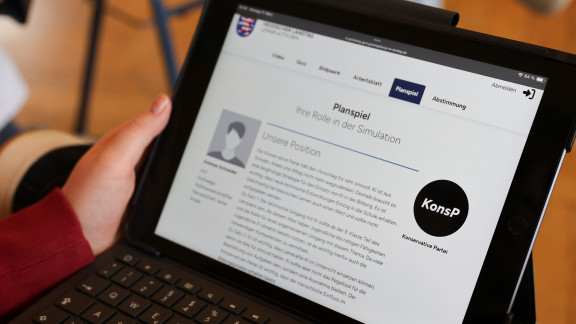 Eine Schülerin hält ein Tablet in Händen. 