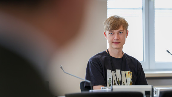 Ein Jugendlicher hört einem Abgeordneten zu.