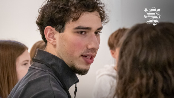 Ein Teilnehmer des Begegnungsprojekts "Meet a Jew" ist im Bild zu sehen. Er spricht mit einer Schülerin.