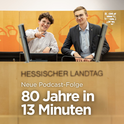 Die beiden FSJler Charlotte und Marius stehen im Plenarsaal hinter dem Rednerpult und lächeln in Richtung Kamera. Der Schriftzug "Neue Podcast-Folge. 80 Jahre in 13 Minuten" ist zu lesen.