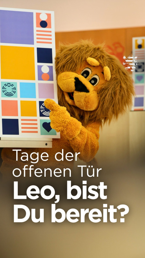 Leo steh tim Plenarsaal und hält ein Plakat in den Pfoten, das die Tage der offenen Tür 2026 bewirbt. Der Schriftzeug "Tage der offenen Tür. Leo, bist du bereit?" ist zu lesen.