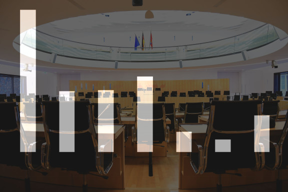 Symbolbild: Ausgegraute Säulengrafik ohne Zahlen vor verdunkeltem Hintergrund des Plenarsaals im Landtag