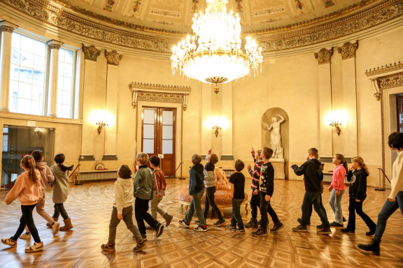 Eine Gruppe Kinder läuft durch den Kuppelsaal mit Kronleuchter.