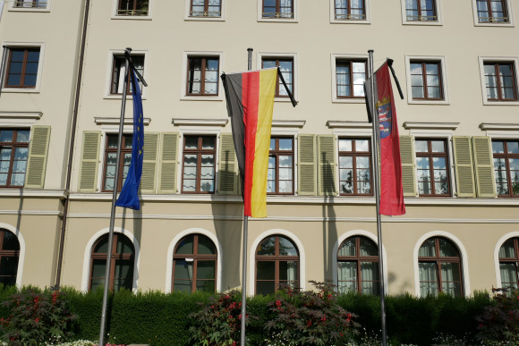 Die europäische, deutsche und hessische Fahne stehen auf Halbmast vor dem hessischen Landtag