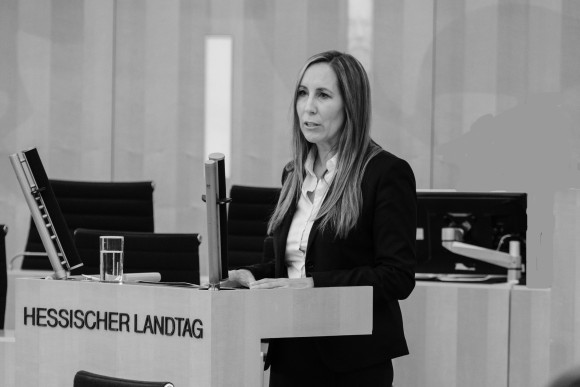 Astrid Wallmann steht am Podium des Hessischen Landtages. Die Fotografie ist in schwarz-weiß.