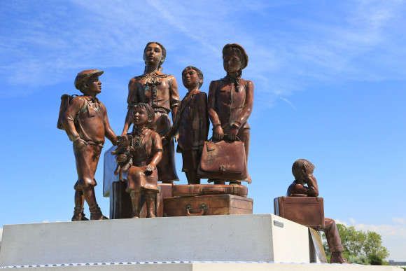 Sechs Bronzefiguren, die Kinder mit Koffern darstellen.