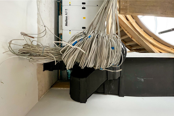 Ein Haufen Kabel hängen vor einem Stromkasten.