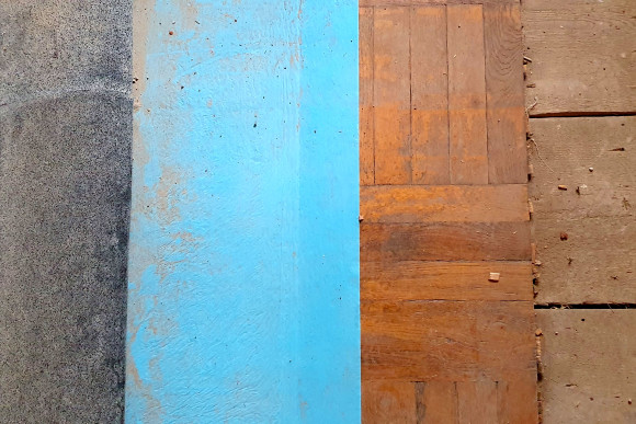 Unter der 2-lagigen Schutzabdeckung aus Gummischrot plus BlueCover ist das Parkett und die Holzdielung darunter zu sehen. 
