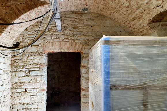 Kellergewölbe im Stadtschloss mit einer Türöffnung, Kabelträgern und Kabeln.