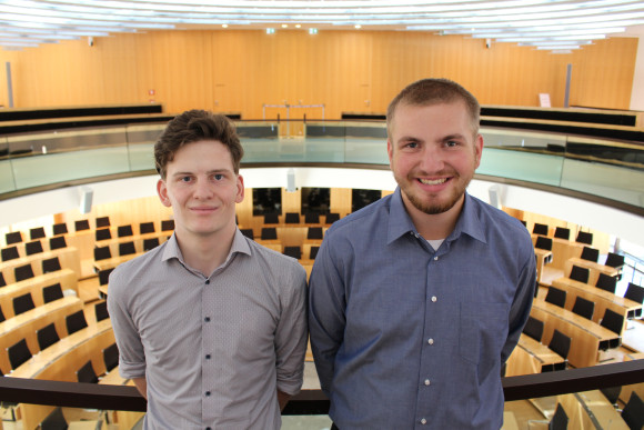 Cornelius Miller und Florian Schmitt auf der Besuchertribüne des Hessischen Landtages mit Blick auf den leeren Plenarsaal