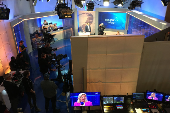 Ein Fernsehstudio im Landtag von außen betrachtet, auch Kameraleute und Technik sind zu sehen