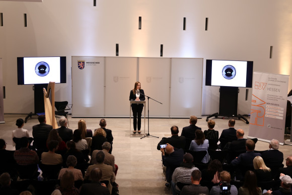 Landtagspräsidentin am Rednerpult vor Publikum in der Ausstellungshalle