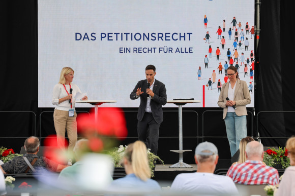 Drei Personen auf Bühne diskutieren