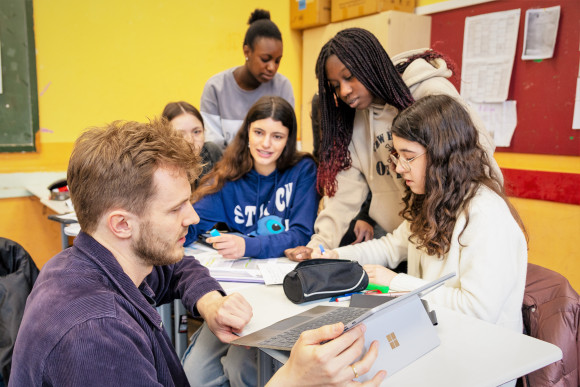 Ein Lehrer bespricht sich mit seinen Schülerinnen. 