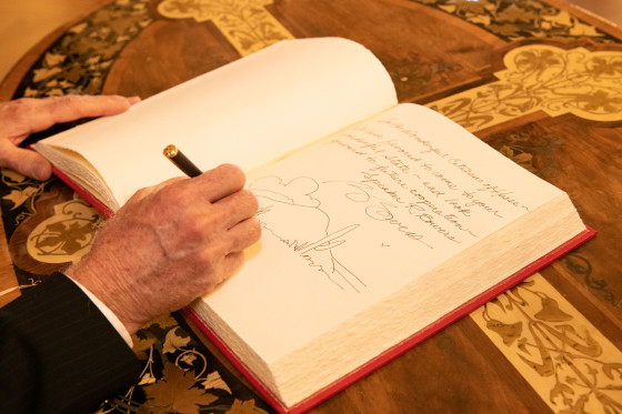 Aufnahme der Hand von Russel Bowers, während er in das Gästebuch schreibt