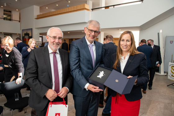 Prof. Dr. Roßnagel, Prof. Dr. von Danwitz und Landtagspräsidentin Astrid Wallmann stehen zusammen und halten eine Box. Diese enthält das hessische Wappen als kleine Statue.