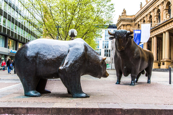 Ein Bär und ein Stier als Bronzefiguren auf einem Platz in einer Stadt. 