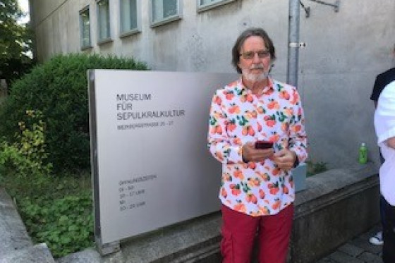 Ein Mann aus der Gruppe der Vereinigung ehemaliger Abgeordneter steht vor dem Eingangsschild des Museums für Sepulkralkultur.