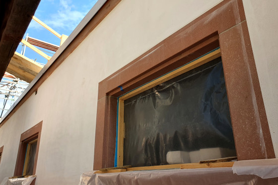 Die verputzte Außenfassade des neu aufgemauerten Mezzanin im DG mit den neuen Fenstereinfassungen aus Sandstein. 