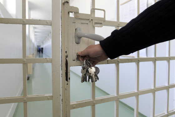 Wärter verschließt eine Gittertür im Gefängnis
