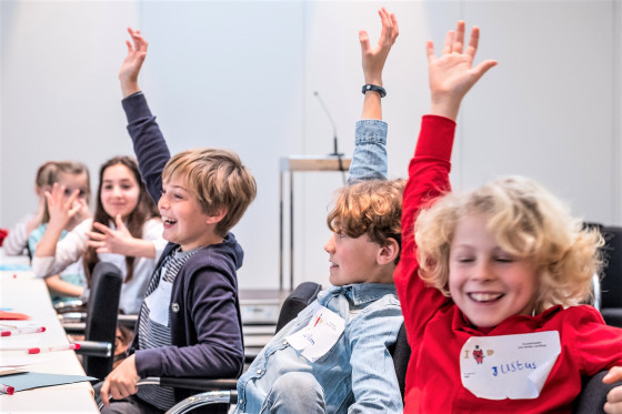 Lachende Kinder stimmen beim Planspiel "Der Kinder-Landtag" über einen Gesetzentwurf ab. 