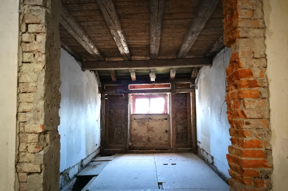 Ein Zimmer auf der Baustelle des Stadtschlosses. Am Ende des Zimmers befindet sich eine Türöffnung, die zur Hälfte mit Holz bedeckt ist.