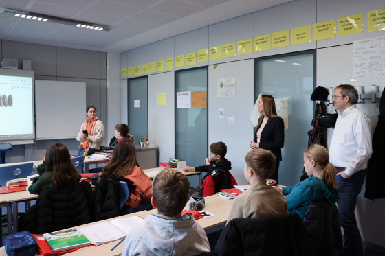 Astrid Wallmann steht in einem Klassenzimmer, in dem gerade Unterricht stattfindet.