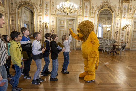 Kinder beim High-Five mit Landtagsmaskottchen Leo