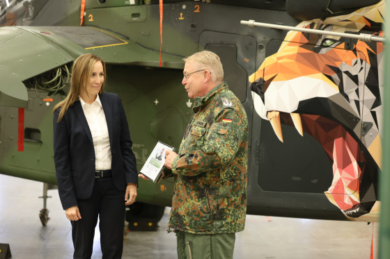 Landtagspräsidentin spricht mit Soldat, dahinter Hubschrauber mit Tiger
