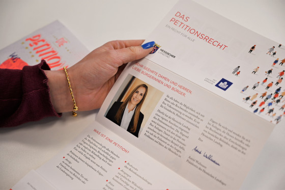 Eine junge Frau hält eine Broschüre zum Thema "Petitionen" in Händen.