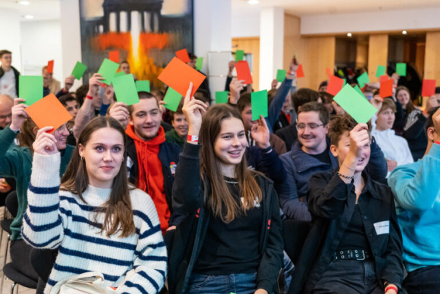 Teilnehmende des Jugendkongresses stimmen mit farbigen Kärtchen über Anträge ab.